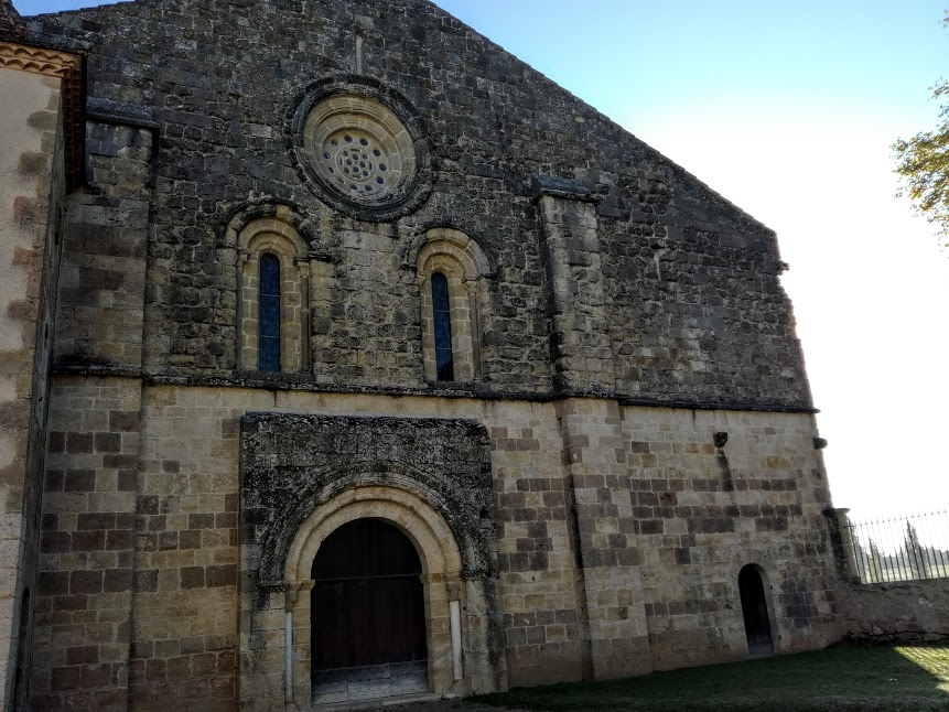 Façade romane de l’abbatiale de Flaran. Cette façade occidentale (XII° - XIII° siècles) est soulignée par deux contreforts. Le porche, sans tympan, qui repose sur les colonnes de piédroits, s'ouvre par une triple voussure. Deux ouvertures en plein cintre, surmontées d'une rose ("oculus"), laissent pénétrer la lumière du couchant, dans la nef. Bâtie en pierre de taille vers 1180, l'église Notre Dame de Flaran est remarquable par ses proportions, par la rigueur de son plan cistercien et par son état de conservation, malgré des dimensions modestes (40 m de long par 19 m de large). Elle demeure caractéristique de l'art roman méridional de la deuxième moitié du XII° siècle (Photo FC)